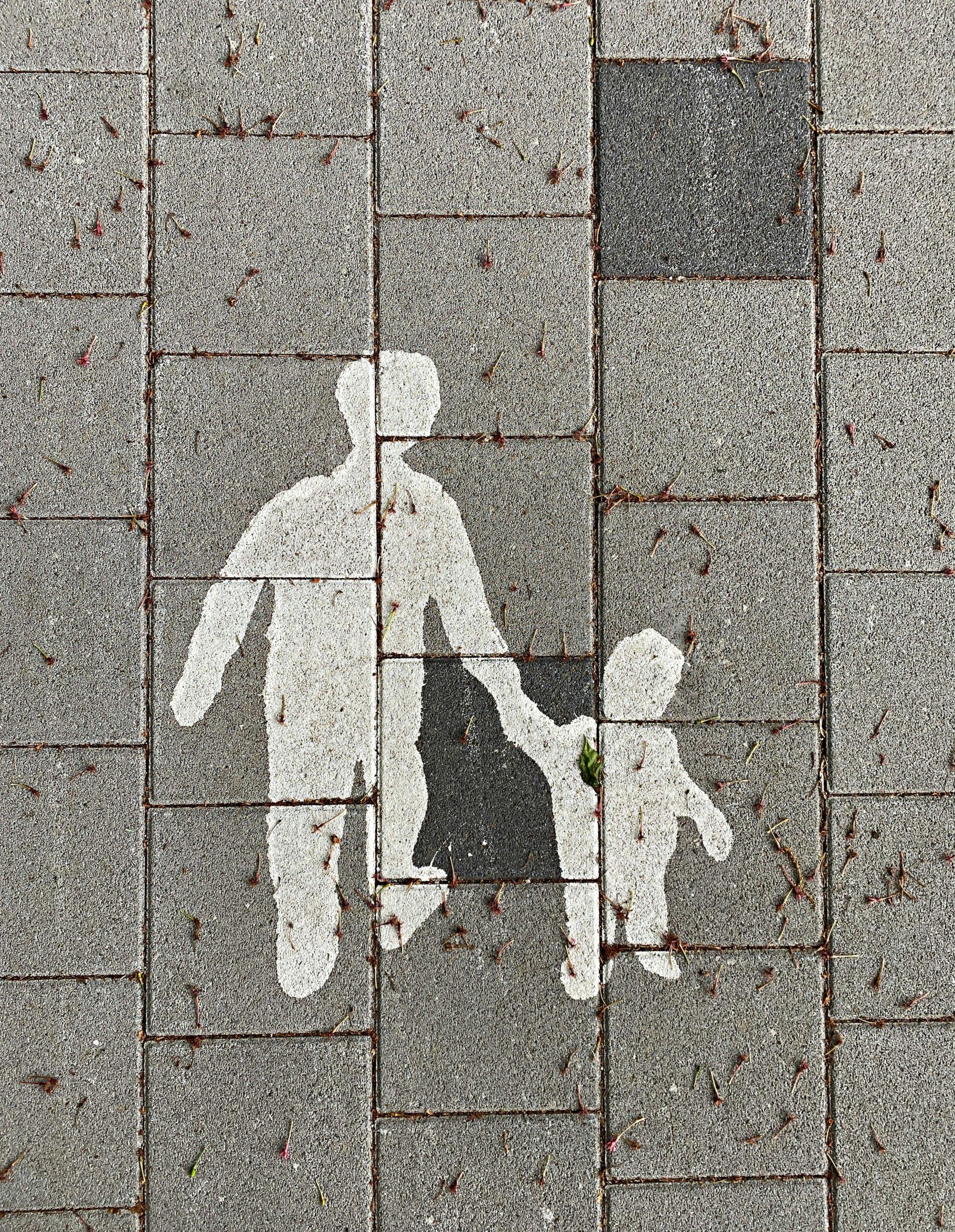 Symbol of a parent hand in hand with a child painted on a pavement