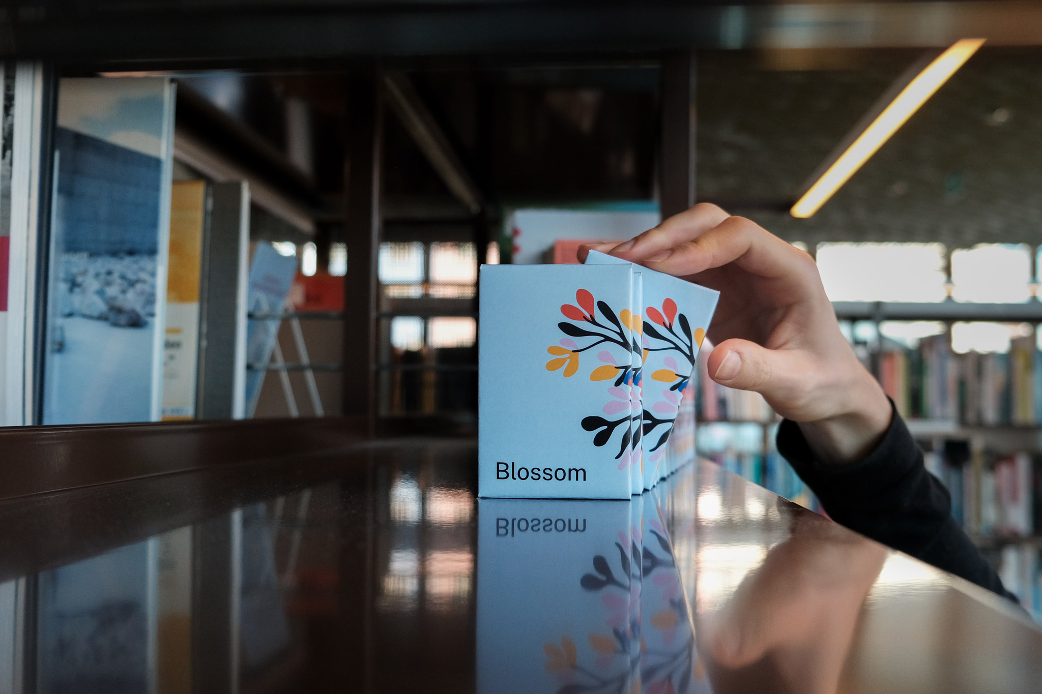 Blossom card games in a library shelf, one being picked out