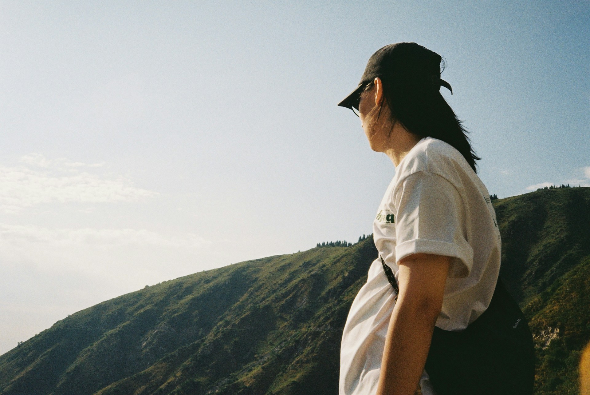 Woman in hat looks at mountains under clear sky