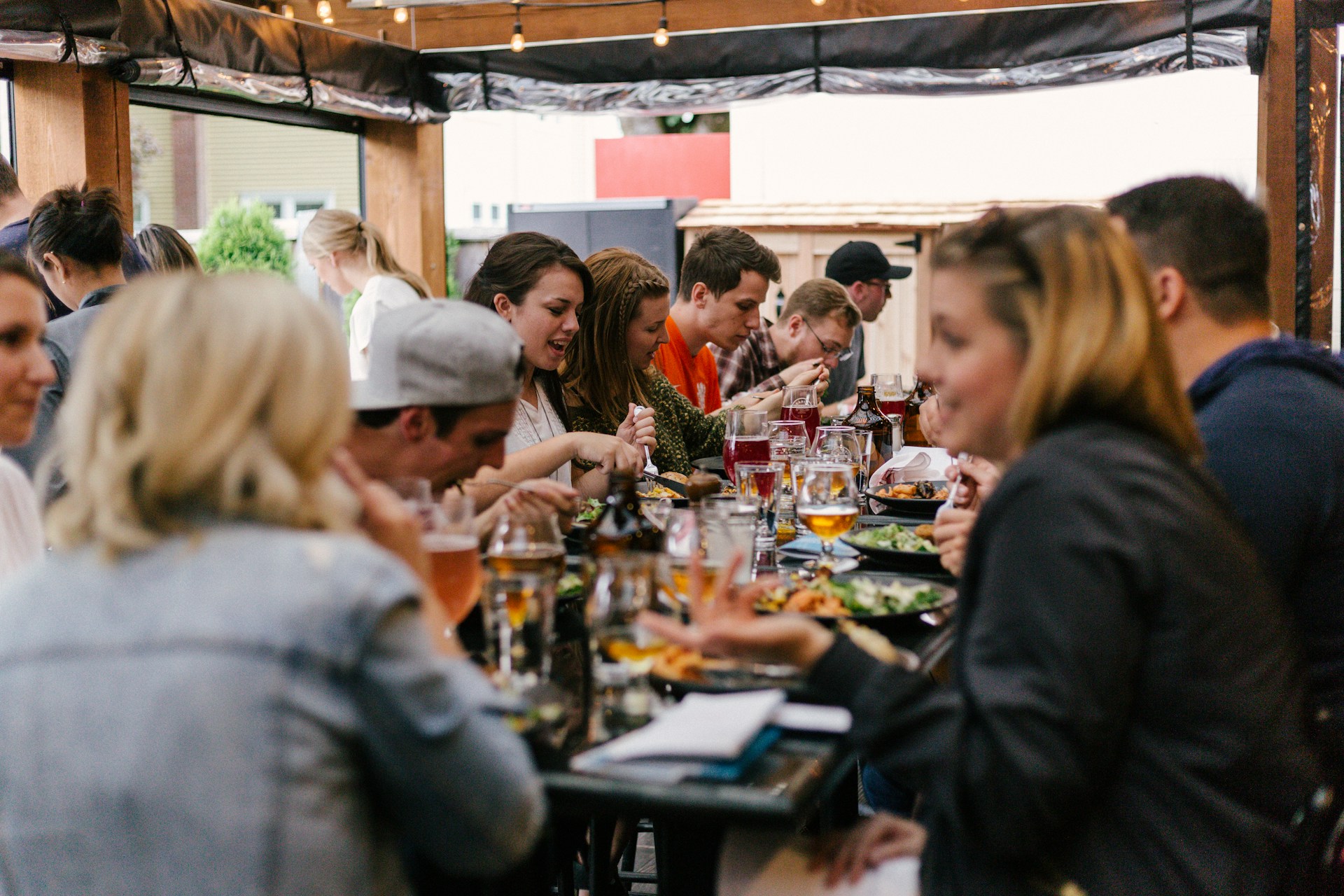 large group of people sitting around a table talking and eating
